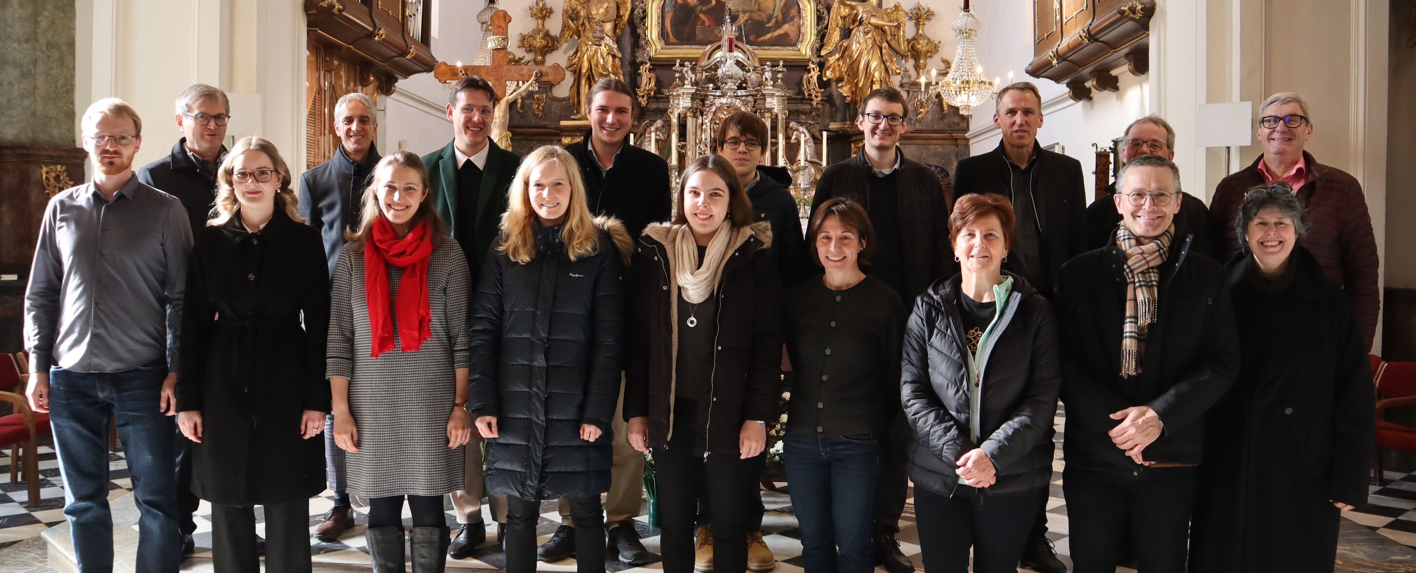 Eine Gruppe von Menschen posiert für ein Foto in einer dekorierten Kirche oder Kapelle.